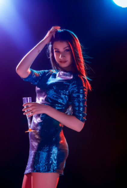 A sexy lady stood in a nightclub wearing a shiny dress
